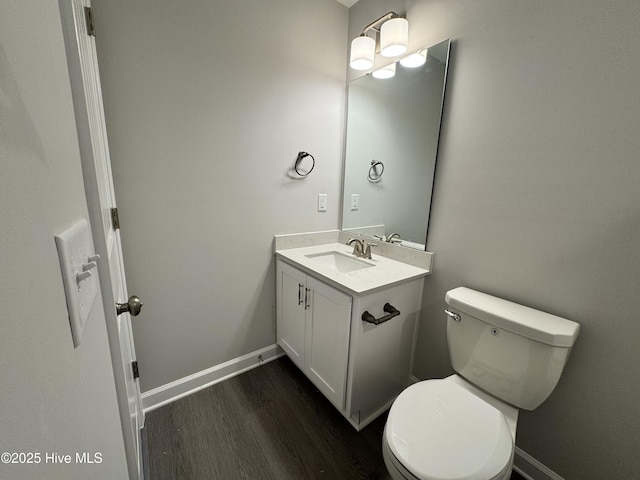 bathroom featuring vanity, toilet, baseboards, and wood finished floors