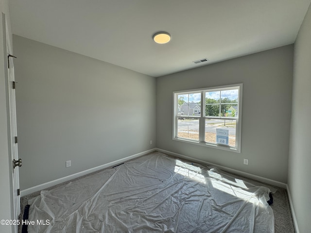 carpeted empty room with visible vents and baseboards