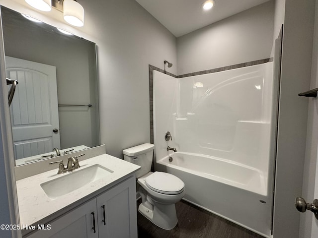 bathroom featuring toilet, vanity, shower / washtub combination, and wood finished floors