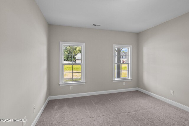 empty room with light colored carpet and vaulted ceiling