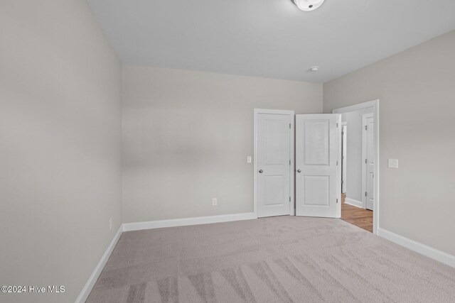 unfurnished bedroom featuring vaulted ceiling, a closet, and light carpet