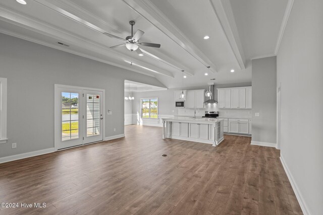 unfurnished living room featuring ceiling fan, a fireplace, light hardwood / wood-style floors, beamed ceiling, and crown molding