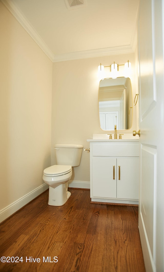 bathroom with wood-type flooring, vanity, toilet, and crown molding