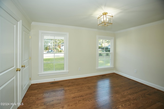 empty room featuring ornamental molding, an inviting chandelier, and dark wood-type flooring