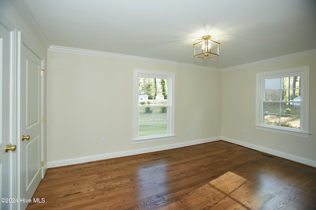 empty room with dark hardwood / wood-style flooring, an inviting chandelier, and ornamental molding