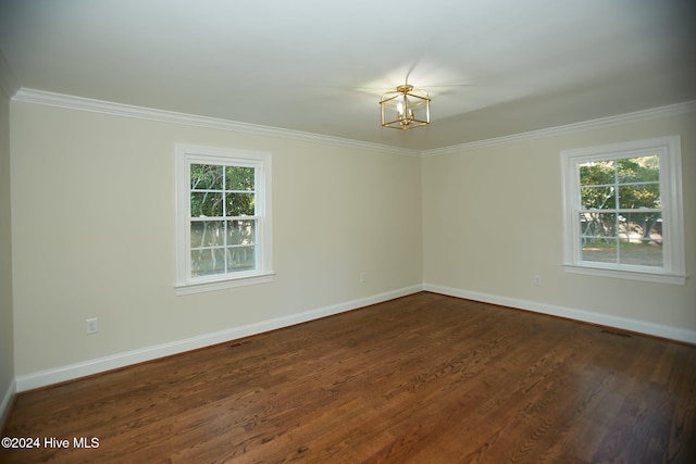 empty room with crown molding, dark hardwood / wood-style floors, and an inviting chandelier