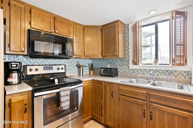 kitchen featuring decorative backsplash, electric range, and sink