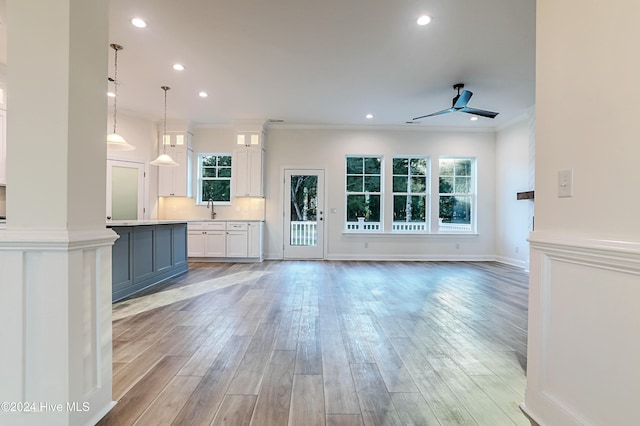 unfurnished living room featuring a wealth of natural light, light hardwood / wood-style flooring, ceiling fan, and ornamental molding