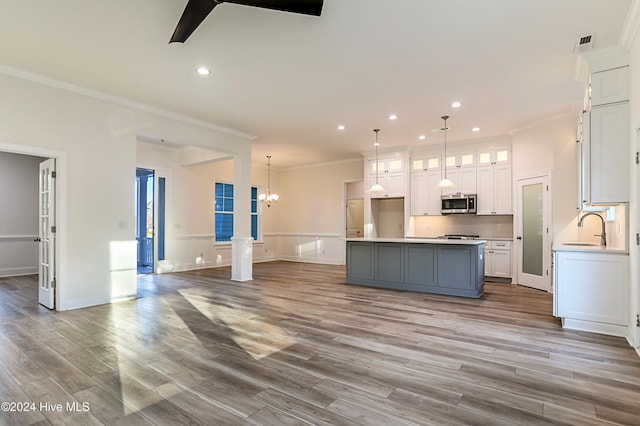 115 Genoes Point Rd SW, Supply, NC 28462 - kitchen featuring stainless steel microwave, ornamental molding, a sink, white cabinetry, and a center island