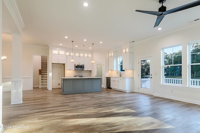 kitchen with white cabinets, light hardwood / wood-style floors, decorative light fixtures, a kitchen island, and appliances with stainless steel finishes