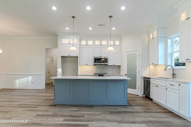 kitchen featuring a center island, sink, stainless steel appliances, decorative light fixtures, and white cabinets