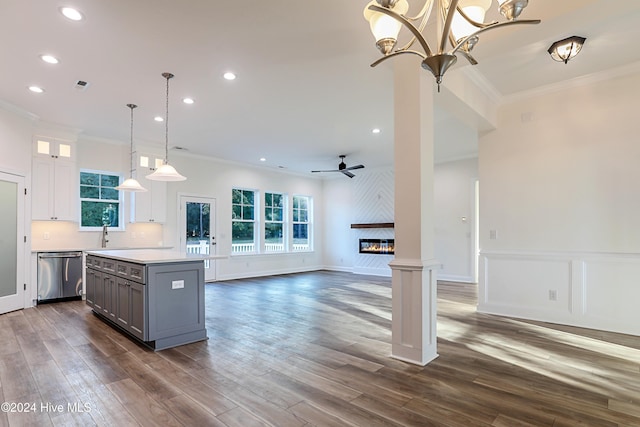 kitchen with white cabinetry, dark wood-type flooring, stainless steel dishwasher, pendant lighting, and ornamental molding