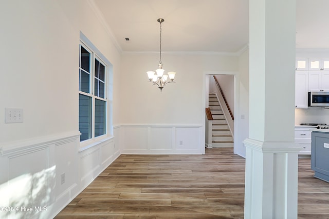 unfurnished dining area with crown molding, a chandelier, and light wood-type flooring