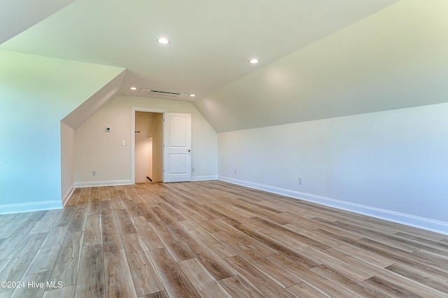 additional living space featuring vaulted ceiling and light wood-type flooring