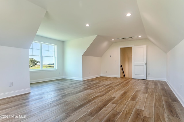 additional living space featuring light wood-type flooring and lofted ceiling