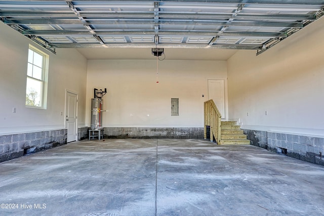 garage featuring electric panel, strapped water heater, and a garage door opener