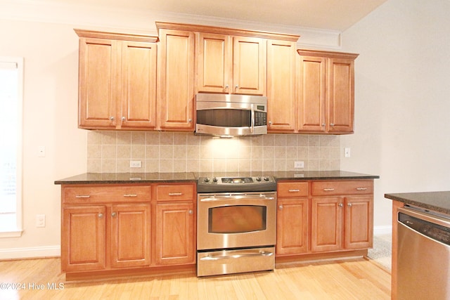 kitchen with decorative backsplash, light hardwood / wood-style flooring, ornamental molding, and appliances with stainless steel finishes