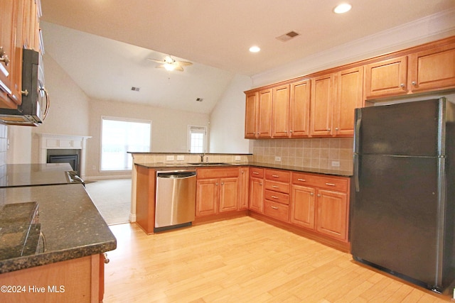 kitchen with dishwasher, kitchen peninsula, vaulted ceiling, black refrigerator, and light wood-type flooring