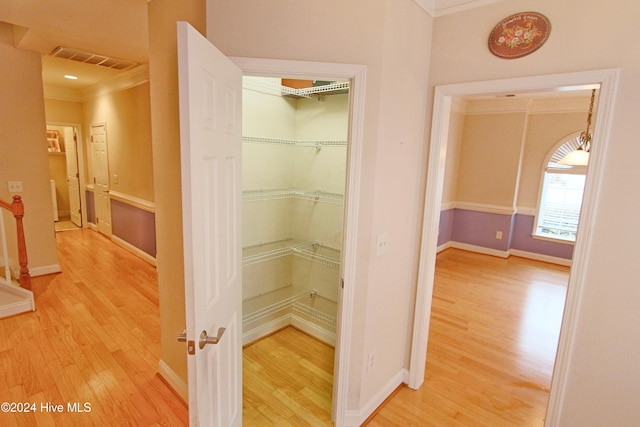 corridor featuring ornamental molding and light wood-type flooring