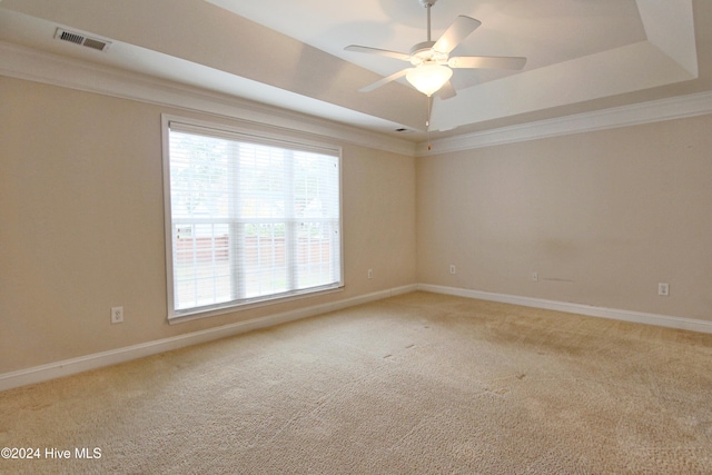 unfurnished room featuring carpet flooring, a raised ceiling, ceiling fan, and crown molding