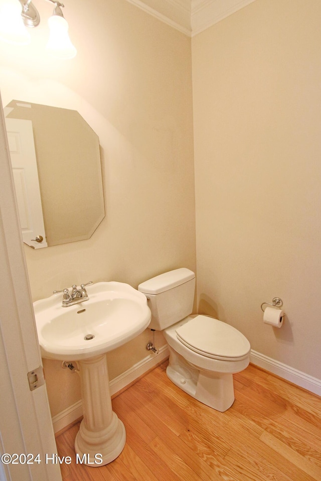 bathroom featuring hardwood / wood-style floors, toilet, ornamental molding, and sink