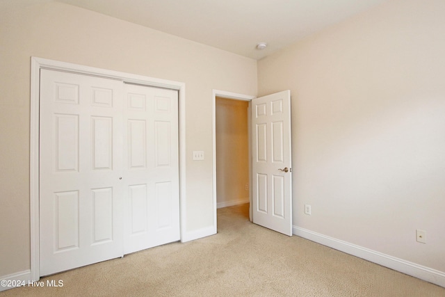 unfurnished bedroom featuring light carpet and a closet