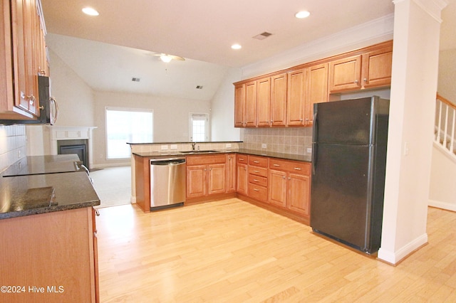 kitchen featuring dishwasher, black fridge, kitchen peninsula, lofted ceiling, and decorative backsplash