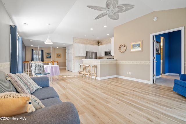 living room with light hardwood / wood-style floors, ceiling fan, and lofted ceiling