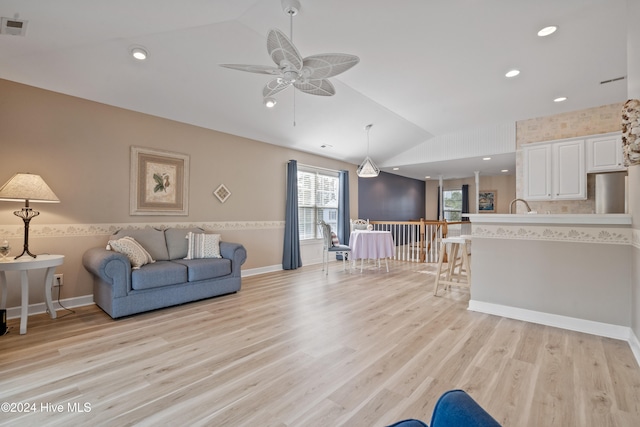 living room featuring light hardwood / wood-style floors, vaulted ceiling, and ceiling fan