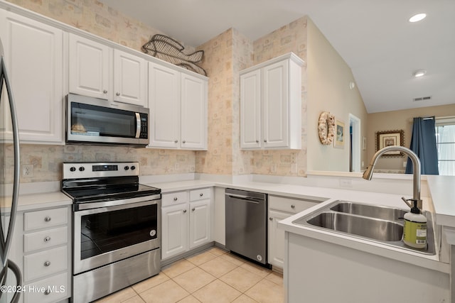 kitchen with white cabinetry, sink, stainless steel appliances, and vaulted ceiling