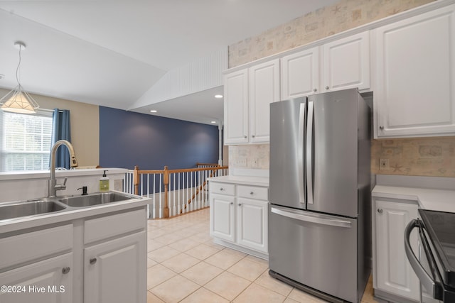 kitchen featuring vaulted ceiling, sink, pendant lighting, white cabinets, and stainless steel refrigerator