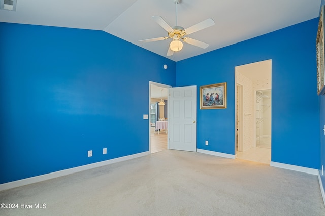 unfurnished bedroom featuring ceiling fan, lofted ceiling, light carpet, and ensuite bath