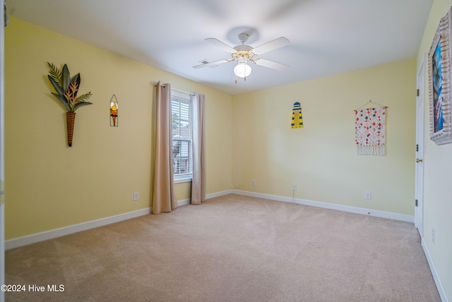 spare room with ceiling fan and light colored carpet