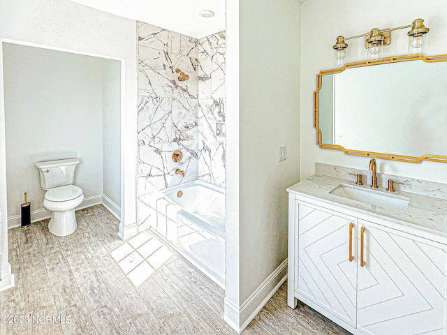 full bathroom featuring vanity, wood-type flooring, tiled shower / bath combo, and toilet