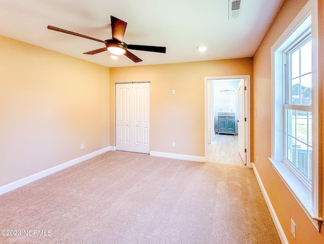 unfurnished bedroom featuring light carpet, a closet, and ceiling fan