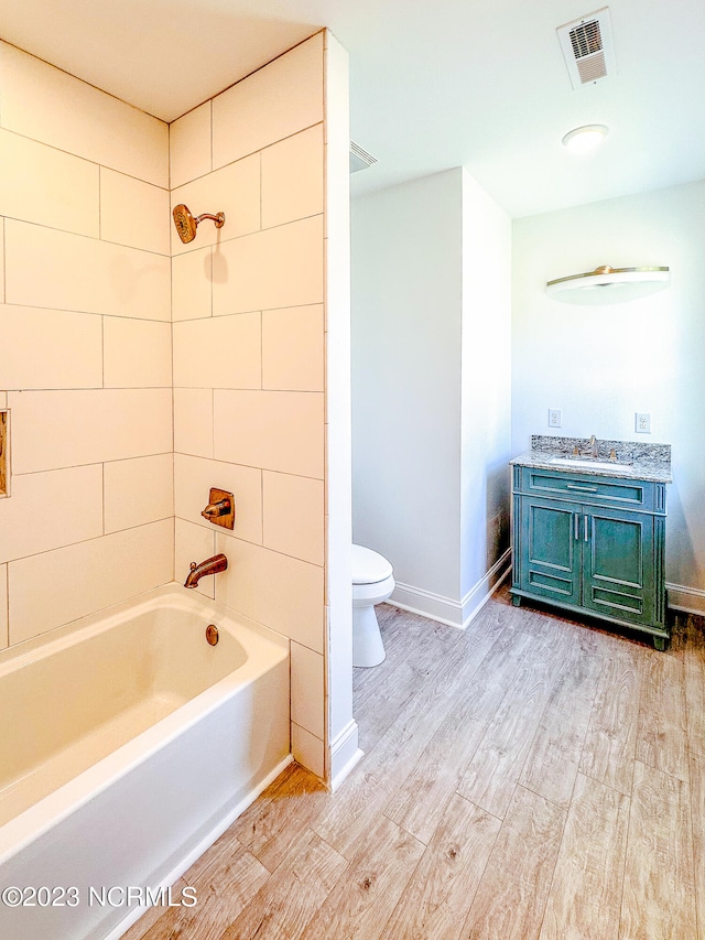 full bathroom featuring tiled shower / bath combo, toilet, wood-type flooring, and vanity