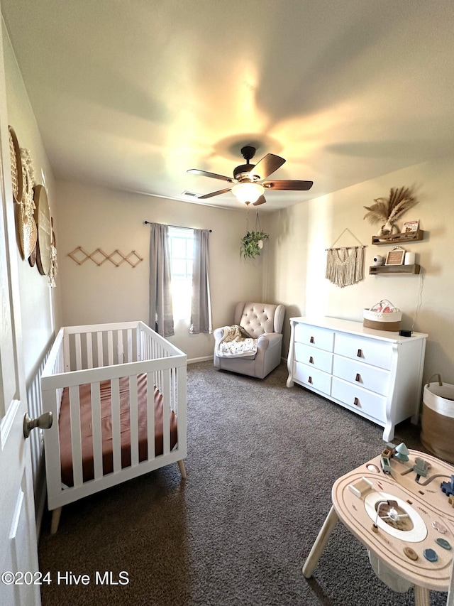 carpeted bedroom with a crib and ceiling fan