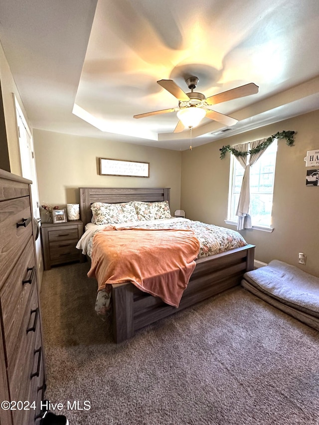 carpeted bedroom featuring a tray ceiling and ceiling fan