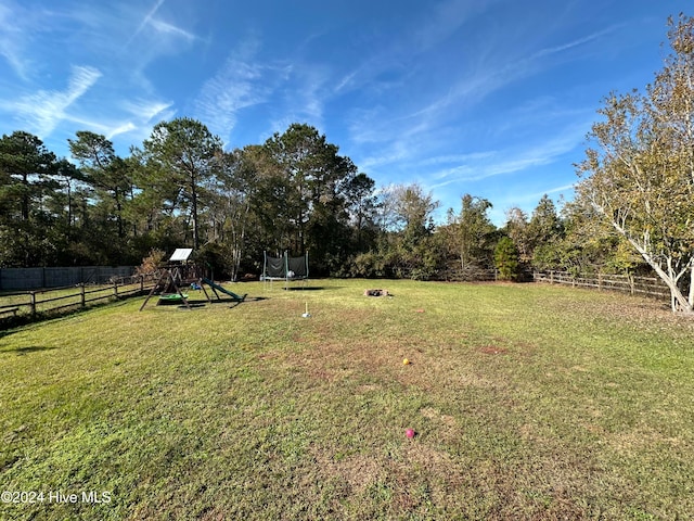 view of yard with a playground and a trampoline