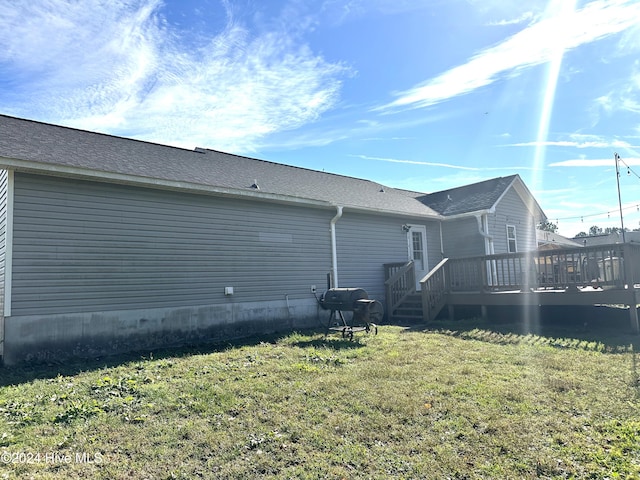 rear view of house with a wooden deck and a yard