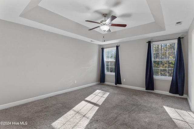 carpeted spare room featuring ceiling fan and a raised ceiling