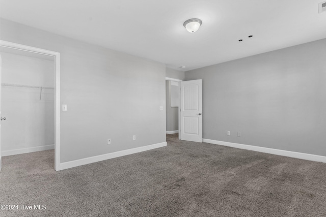 unfurnished bedroom with a walk in closet, a closet, and carpet