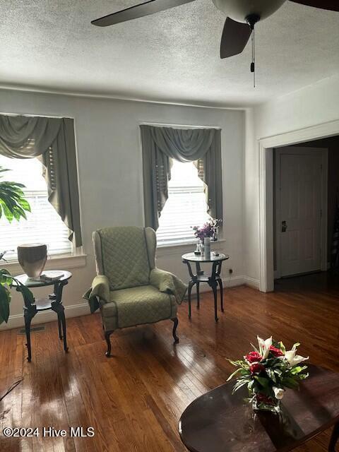 living area featuring hardwood / wood-style floors, a textured ceiling, and ceiling fan