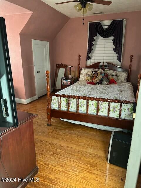 bedroom with light hardwood / wood-style floors, vaulted ceiling, and ceiling fan