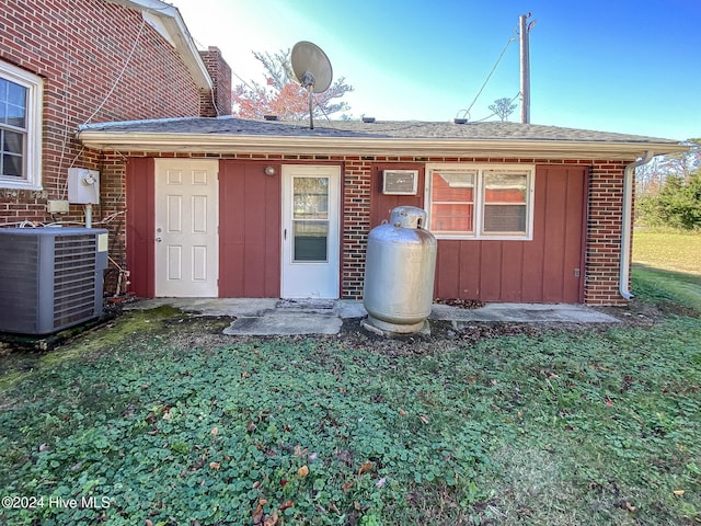 back of property with a lawn and central AC