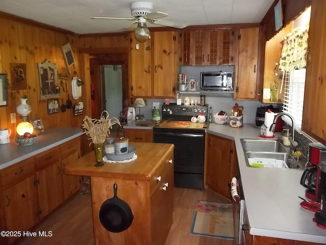 4271 Caratoke Hwy, Barco, NC 27917 - kitchen with black appliances, ceiling fan, brown cabinets, a kitchen island, and wood walls