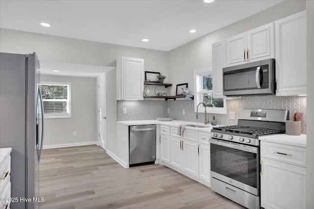 kitchen with sink, white cabinets, light hardwood / wood-style flooring, and appliances with stainless steel finishes