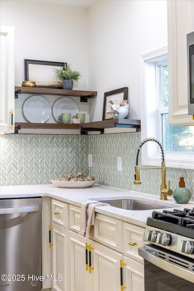 kitchen featuring light stone countertops, stainless steel appliances, tasteful backsplash, and sink