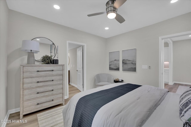 bedroom featuring ceiling fan, ensuite bathroom, and light hardwood / wood-style floors