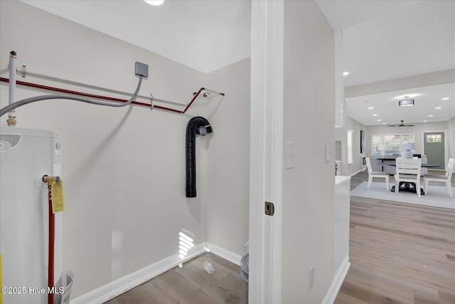 workout room featuring water heater, ceiling fan, and light hardwood / wood-style floors